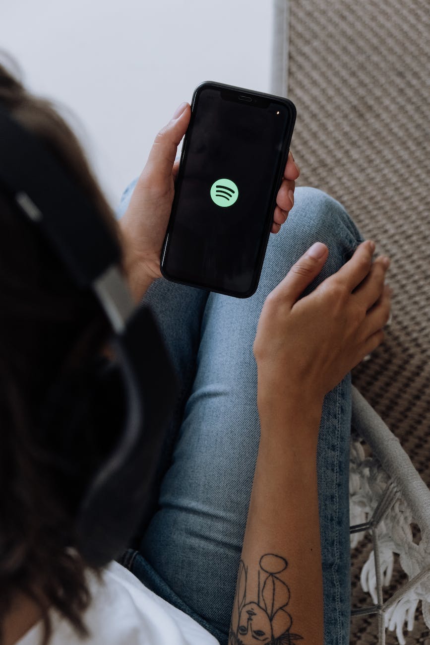 woman holding cell phone with spotify logo on it
